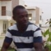 Man in striped shirt sitting outside modern houses