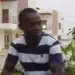 Man in striped shirt sitting outside modern houses
